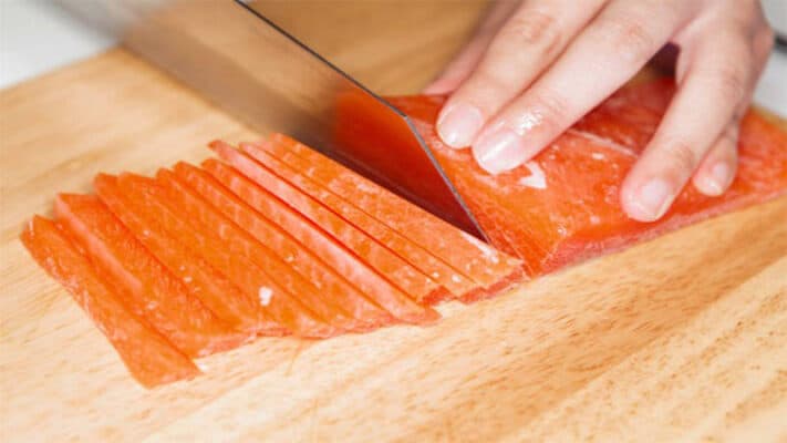 Hình ảnh minh họa đầu bếp cắt miếng cá hồi vừa đủ ăn